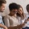 young adults sit on couch looking at each other's cell phones