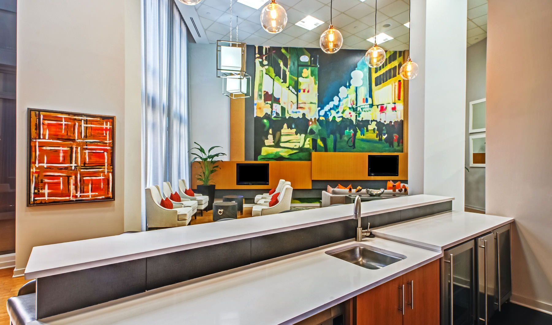 kitchen countertop with sink looks out into brightly lit clubhouse